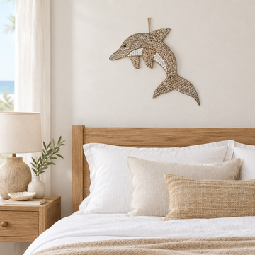 Shell-covered dolphin decoration hanging above a timber bed in a coastal bedroom.