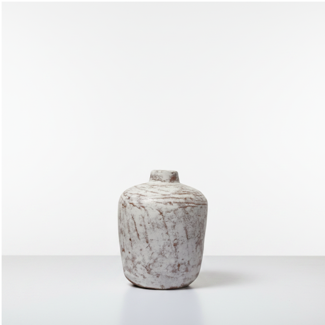 Small squat white wash vase with mottled rustic texture on a light surface