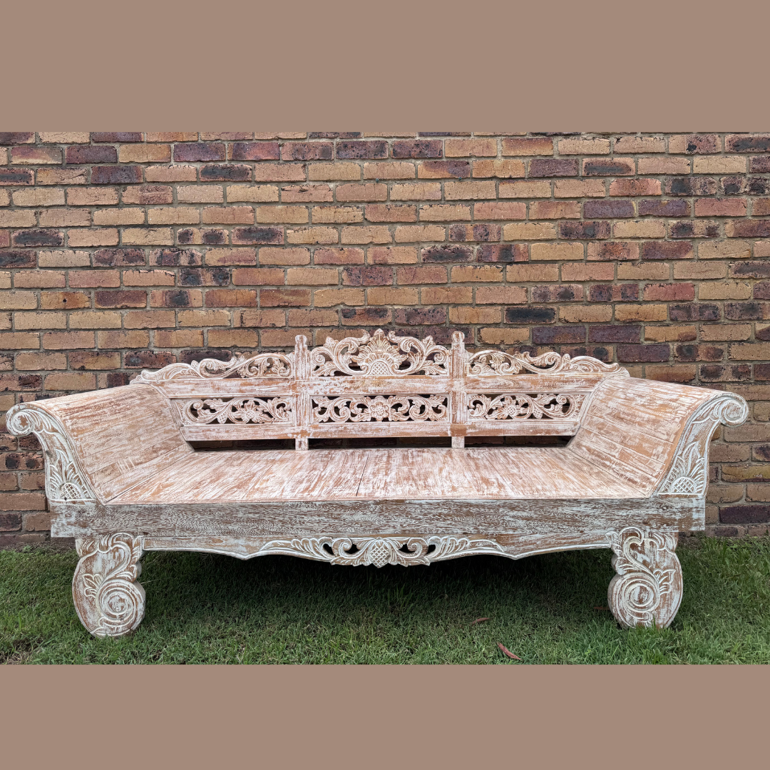 Carved wooden bench in front of a brick wall