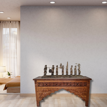 Wooden table with carvings in a room with a bed and window