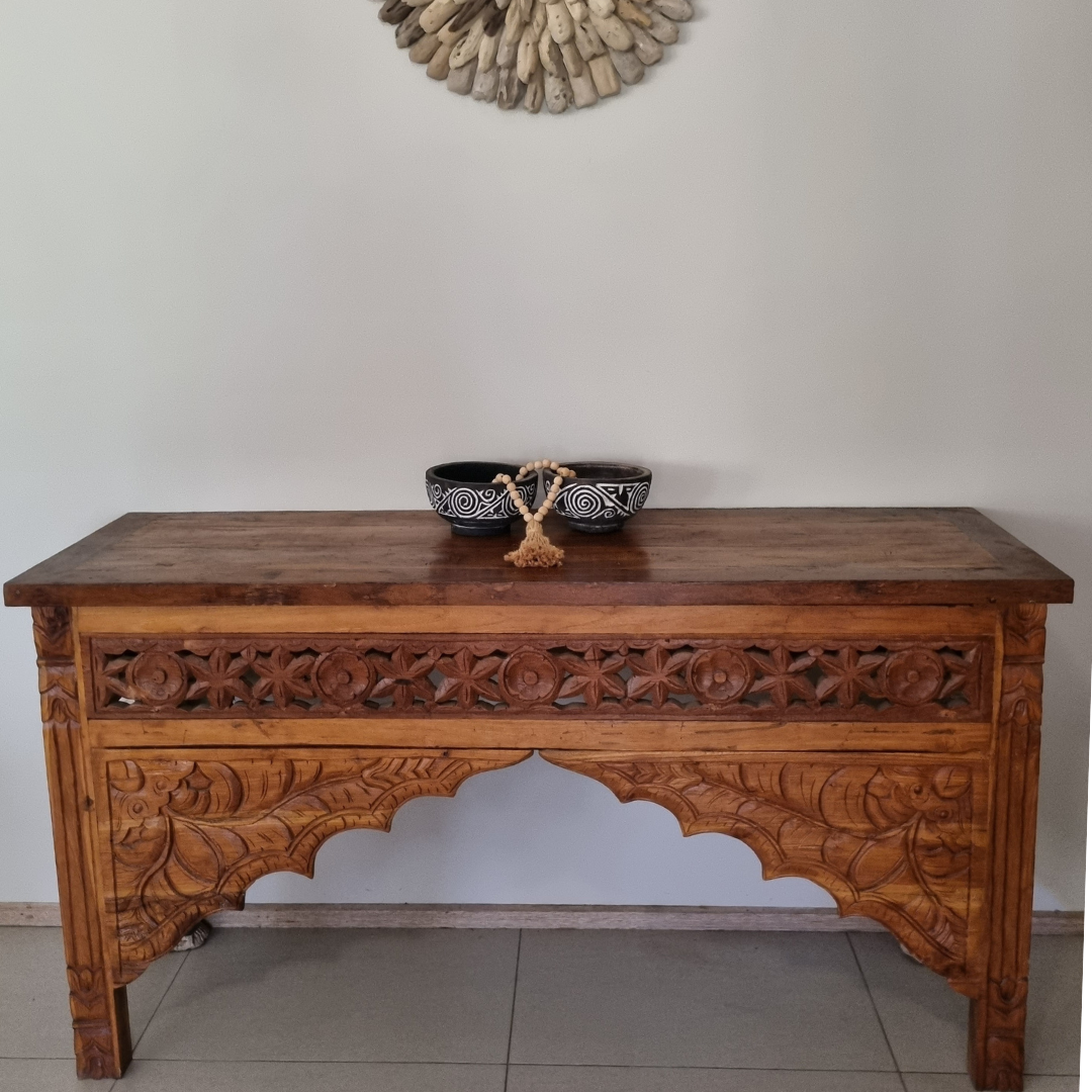 Balinese style reclaimed teak console table in a real home setting – close view showing intricate hand-carved floral and arch detailing with driftwood wall art above, handcrafted furniture by Azure Decor