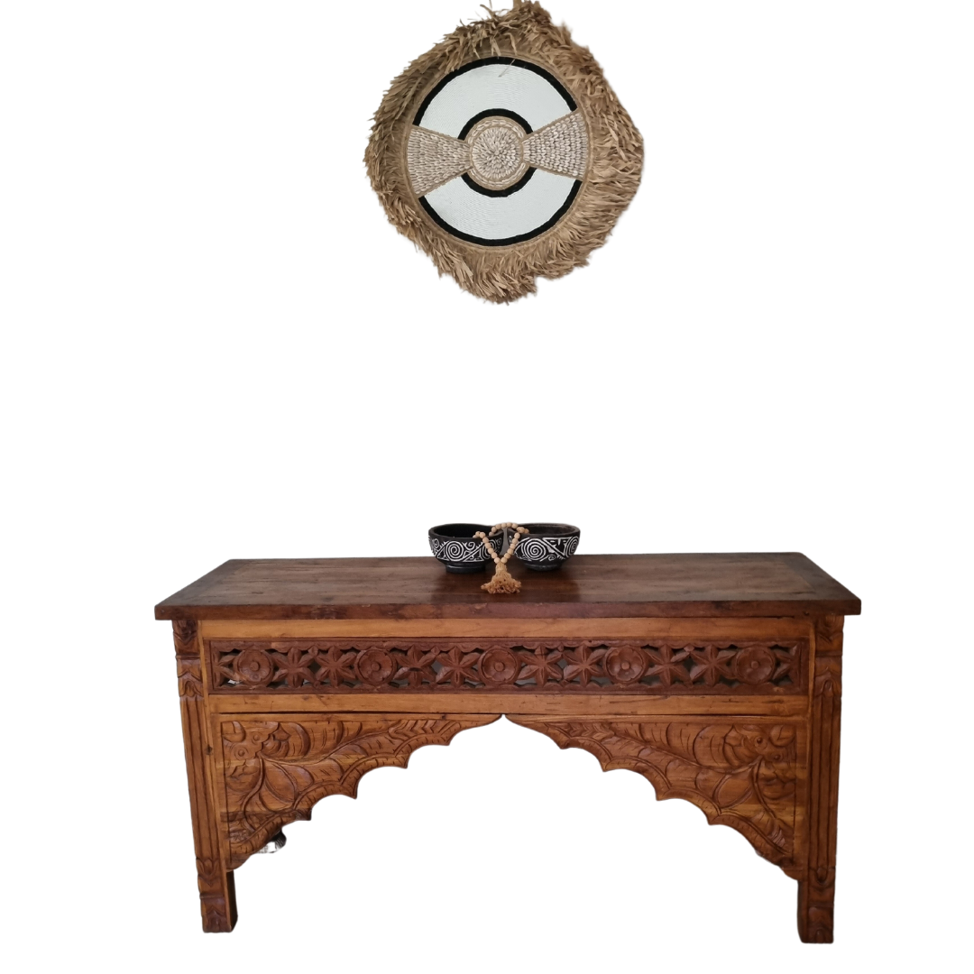 circular beaded and shell - seagrass wall art with a wooden balinese cabinet and wooden bowls on top with beded wooden decor 