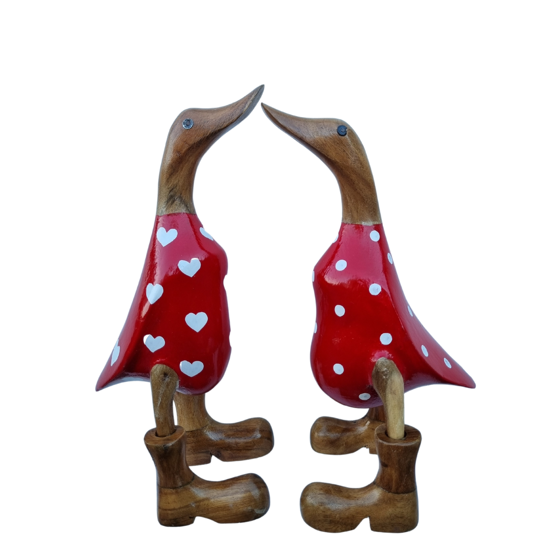 Two bamboo red ducks facing each other, one with white hearts and one with white polka dots, both wearing brown boots.