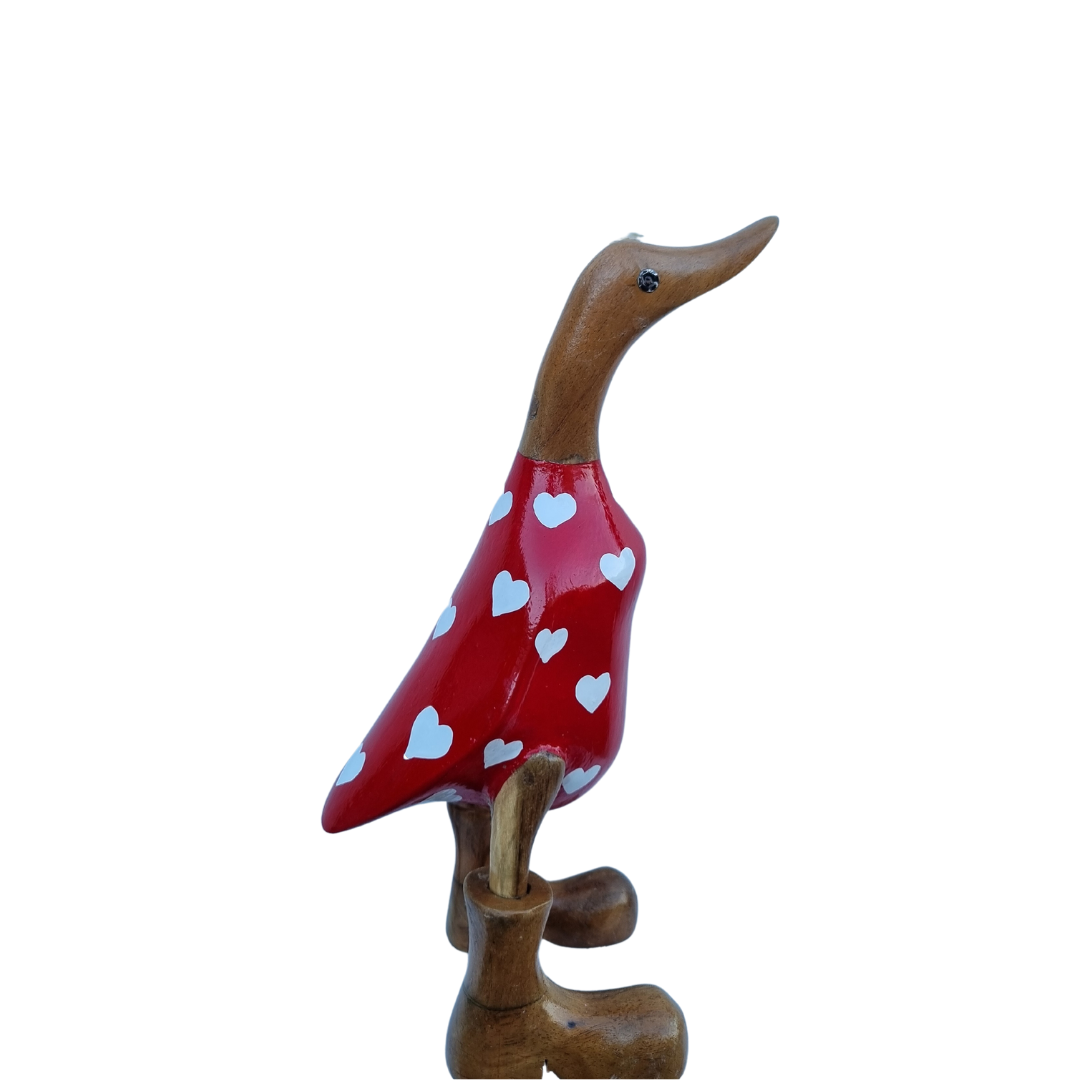Side view of a glossy scarlet body with white hearts, a curved natural timber neck and brown boots