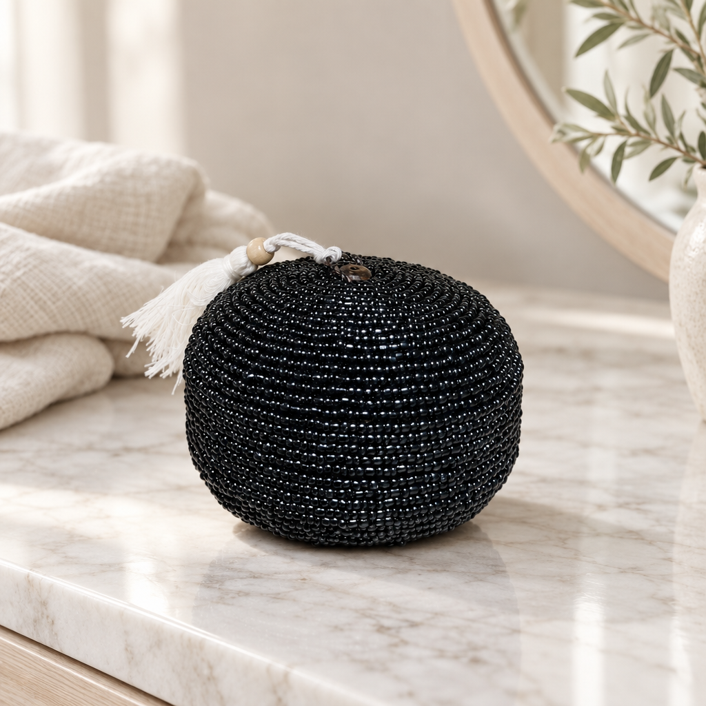 Black round beaded piece styled on a pale marble vanity