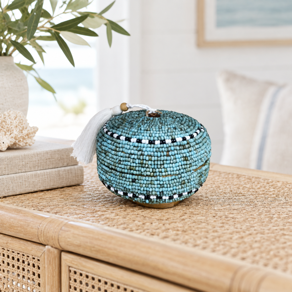 Teal-blue round beaded piece styled on a pale rattan console