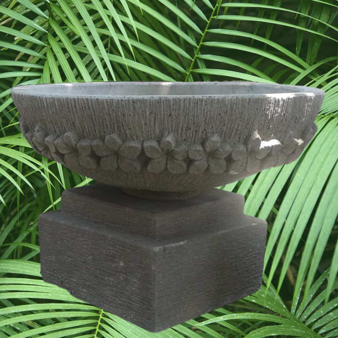 Decorative bowl on a pedestal with green foliage in the background