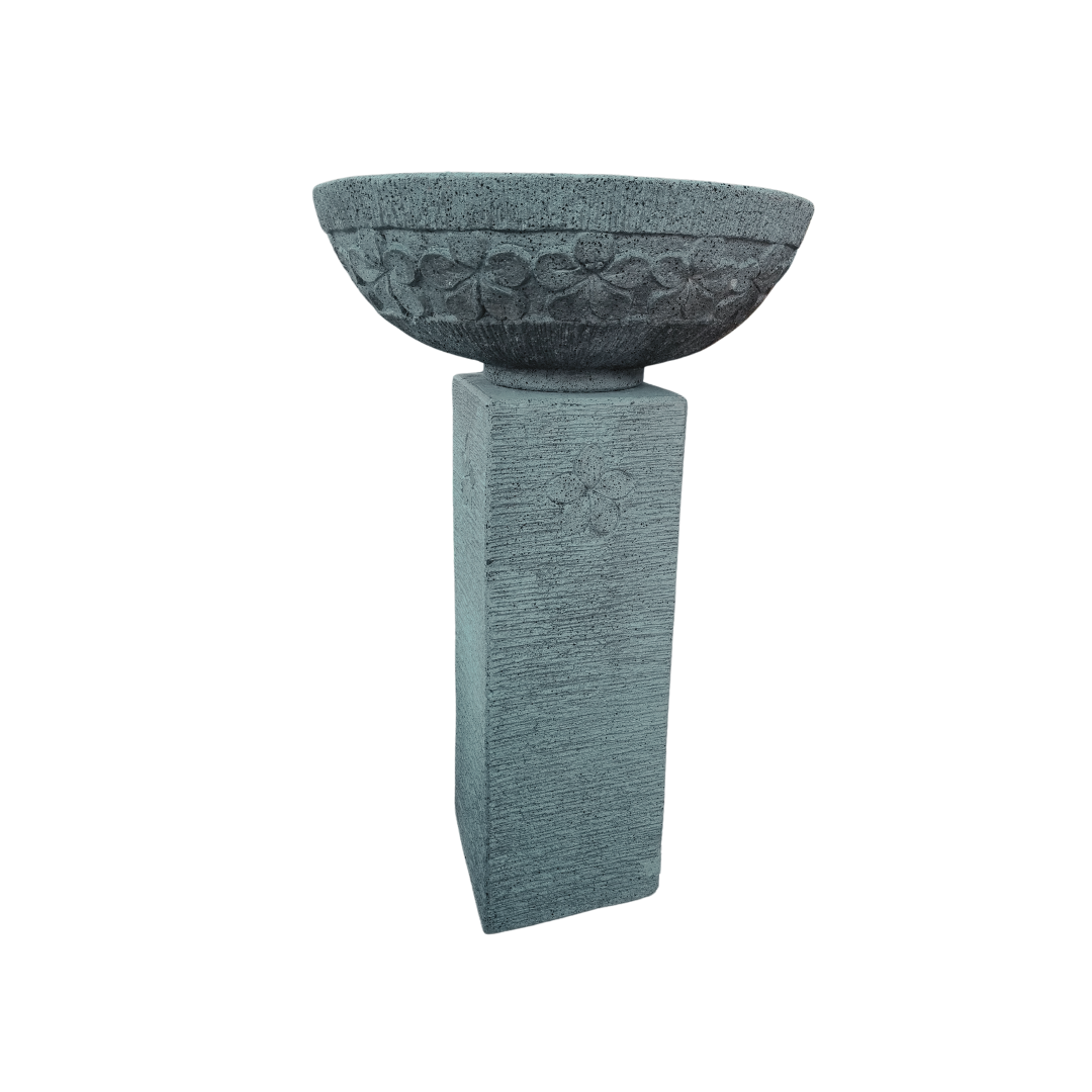 Decorative concrete bowl on a pedestal with intricate carvings against a white background