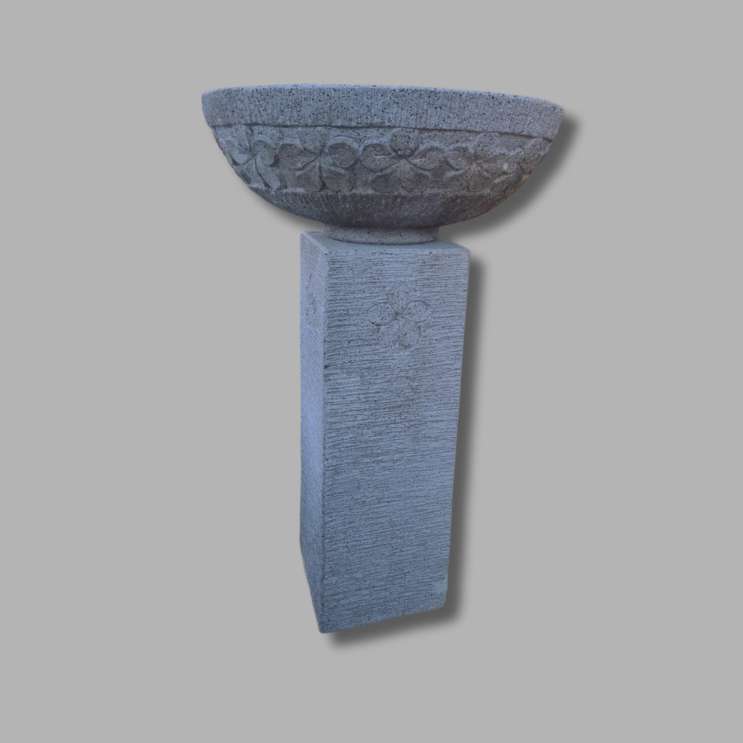 Decorative conctret birdbath pedestal with bowl on a gray background
