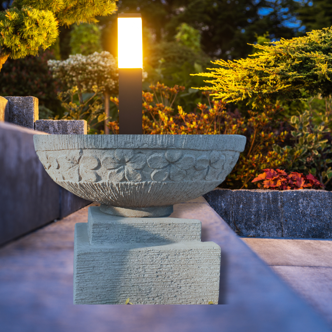 Decorative stone bowl with floral patterns in a garden setting