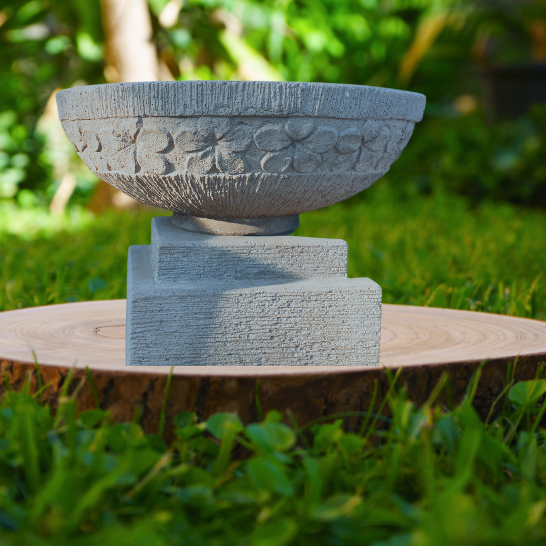 Decorative bowl on a wooden platform with greenery in the background