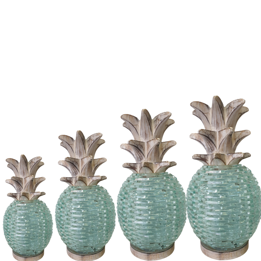 Four sizes of Boho Glass Pineapple Décor displayed together — small, medium, large and extra large — featuring aqua sea-glass textured bodies with whitewashed carved wooden leaf tops, handcrafted tropical boho tabletop sculpture by Azure Decor