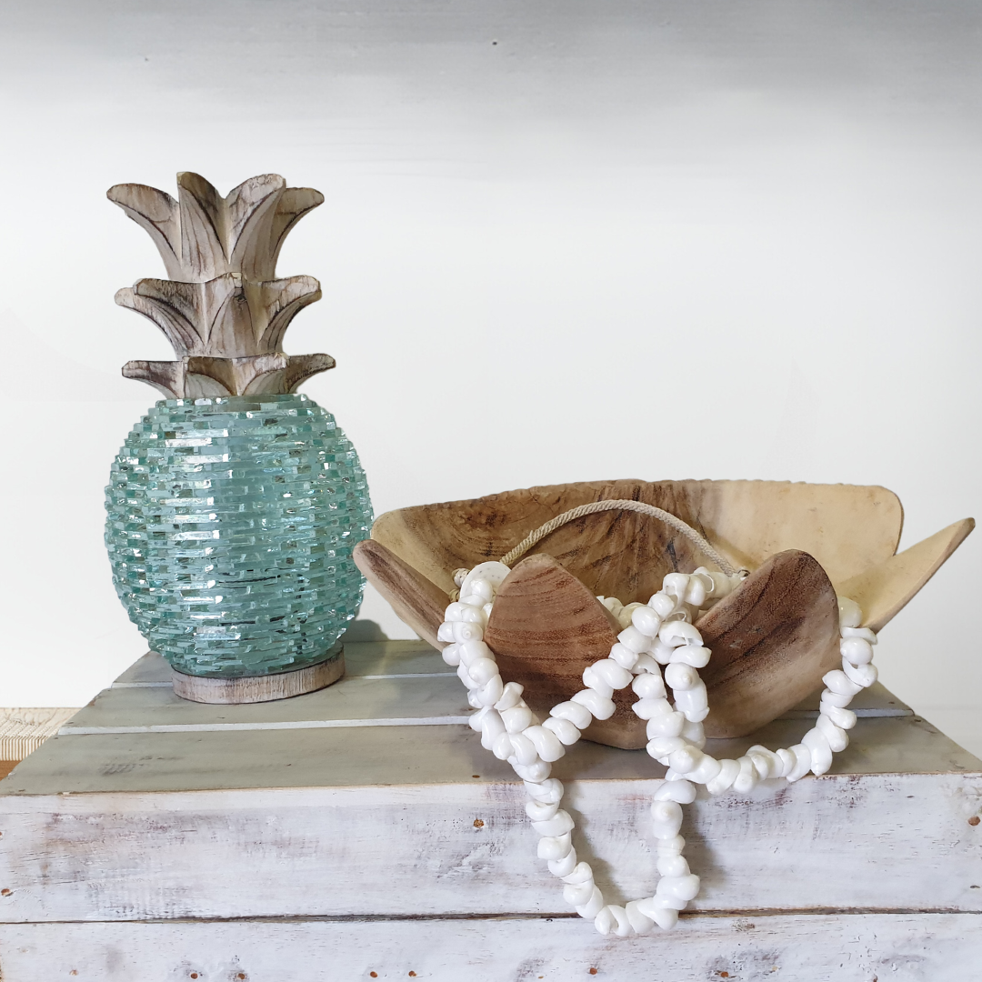 Boho Glass Pineapple Décor in aqua sea-glass with whitewashed carved wooden leaf top, styled on a whitewashed timber shelf alongside a rustic wooden dough bowl filled with white shell bead garland — coastal boho tabletop sculpture by Azure Decor