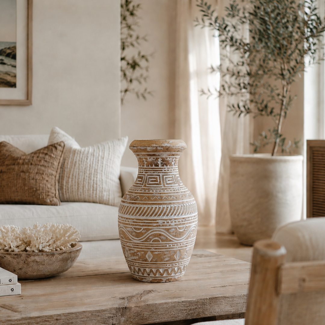 Decorative vase on a table in a living room with a couch and plants.