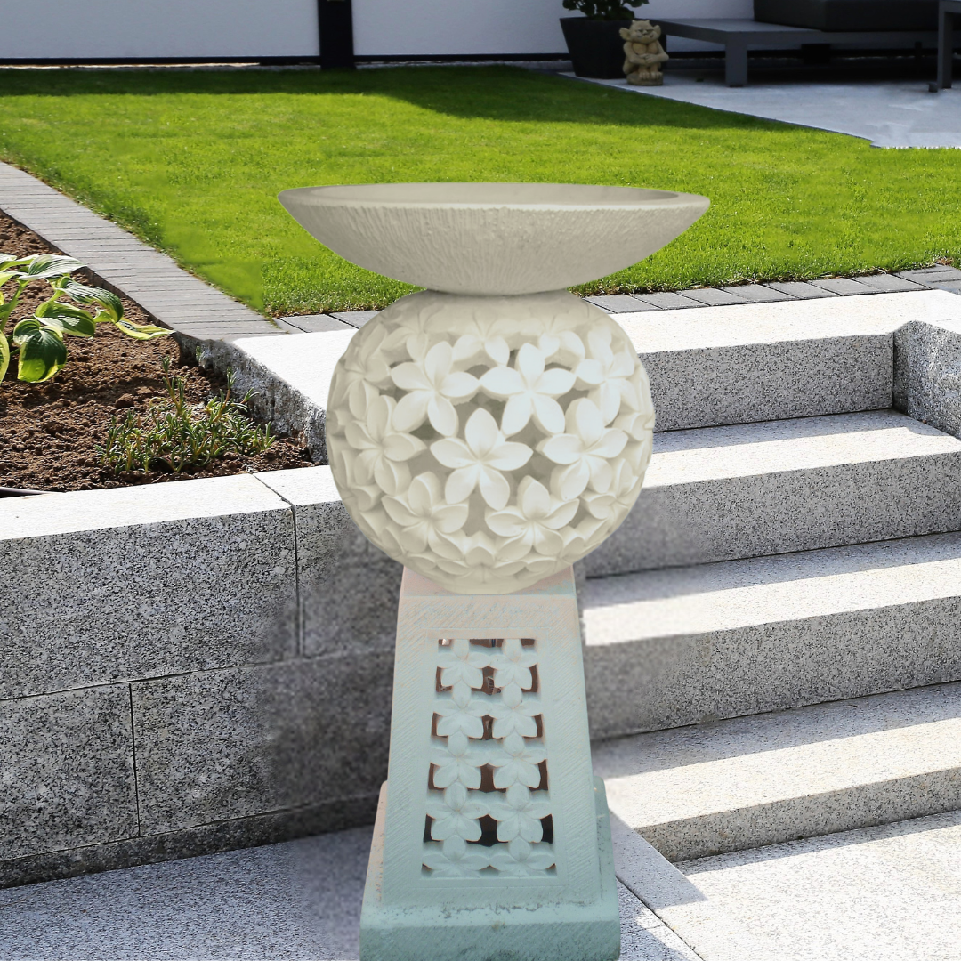 Decorative stone pedestal with floral design in a garden setting