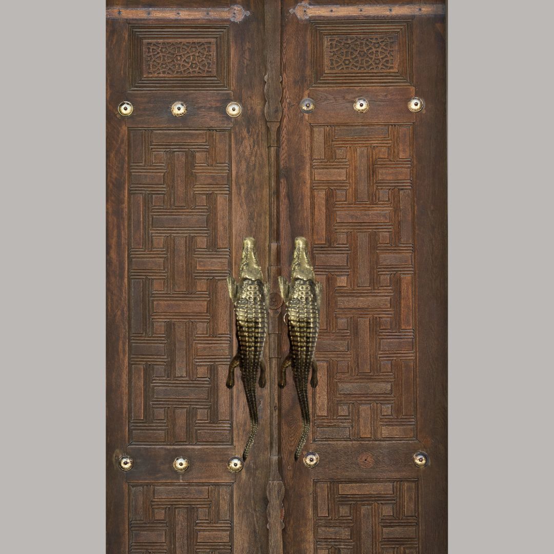 Pair of solid brass crocodile door handles mounted on ornate carved double timber doors with brass stud detailing – decorative brass hardware Australia