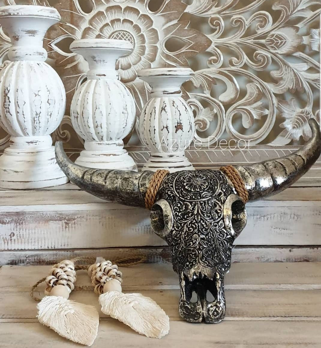 syle 2 Silver metalic cow skull on table top with other decorative items candle handles white wash and macrame shell leaf art 