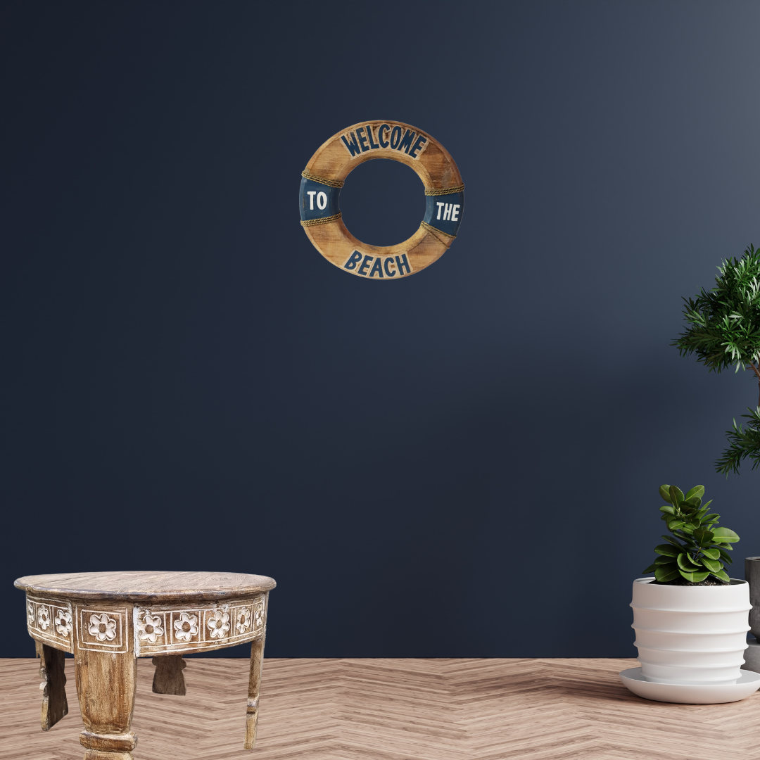 Decorative wall sign with 'Welcome to the Beach' text on a dark blue wall above a wooden table.