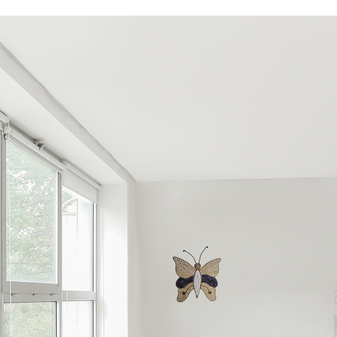 A wall-mounted Butterfly Shell Artwork made from assorted shells, predominantly in shades of brown and white, with a butterfly silhouette in the center.