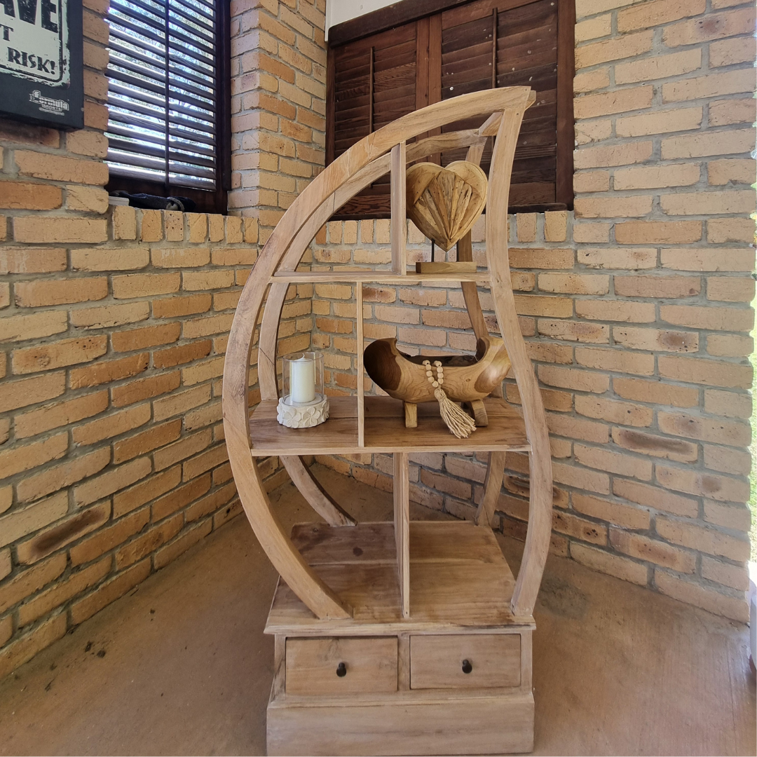 Wooden circular shelf with decorative items against a brick wall.