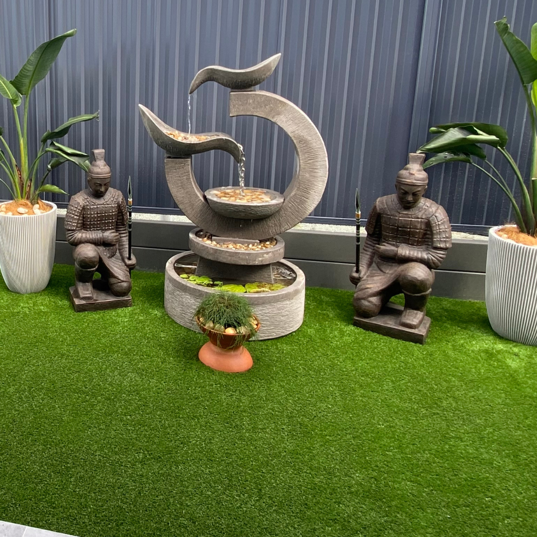 Decorative fountain with statues on a grassy area