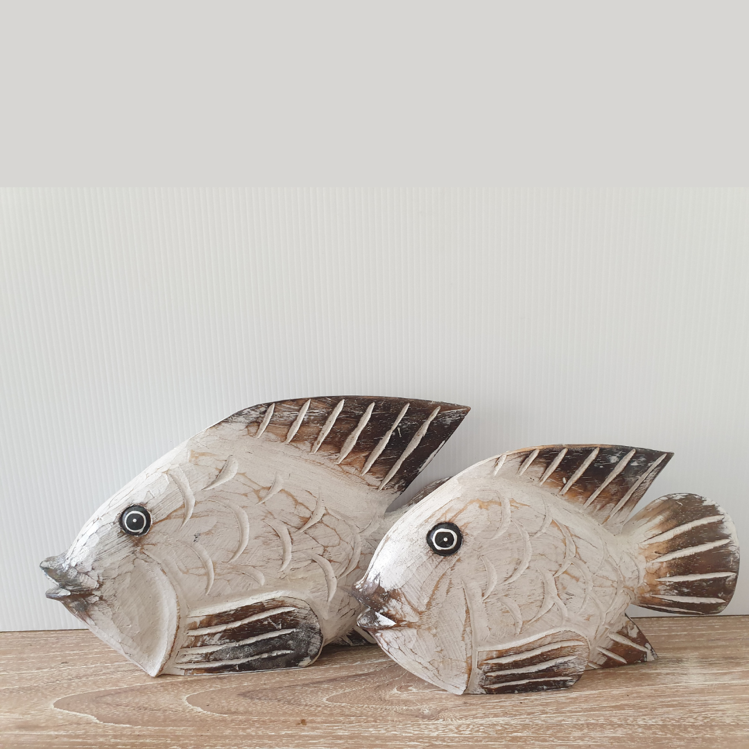 Decorative fish sculptures on a wooden surface with a light background