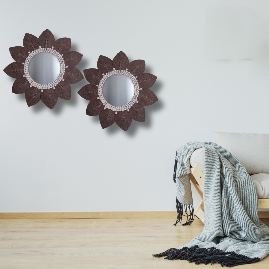 Two decorative macrame mirrors with floral designs on a wall above a bench with a blanket.