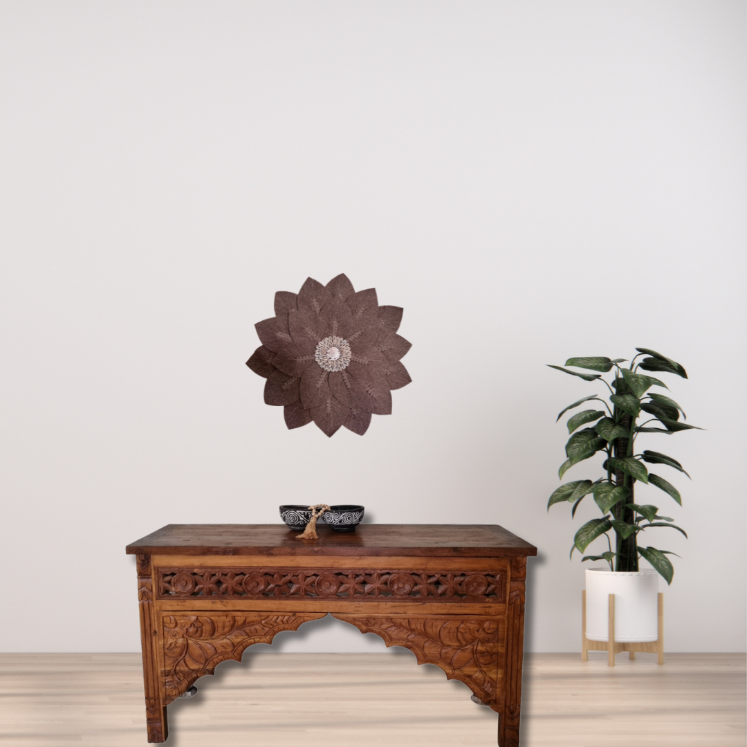 Decorative wall art above a wooden table with a plant on a light background