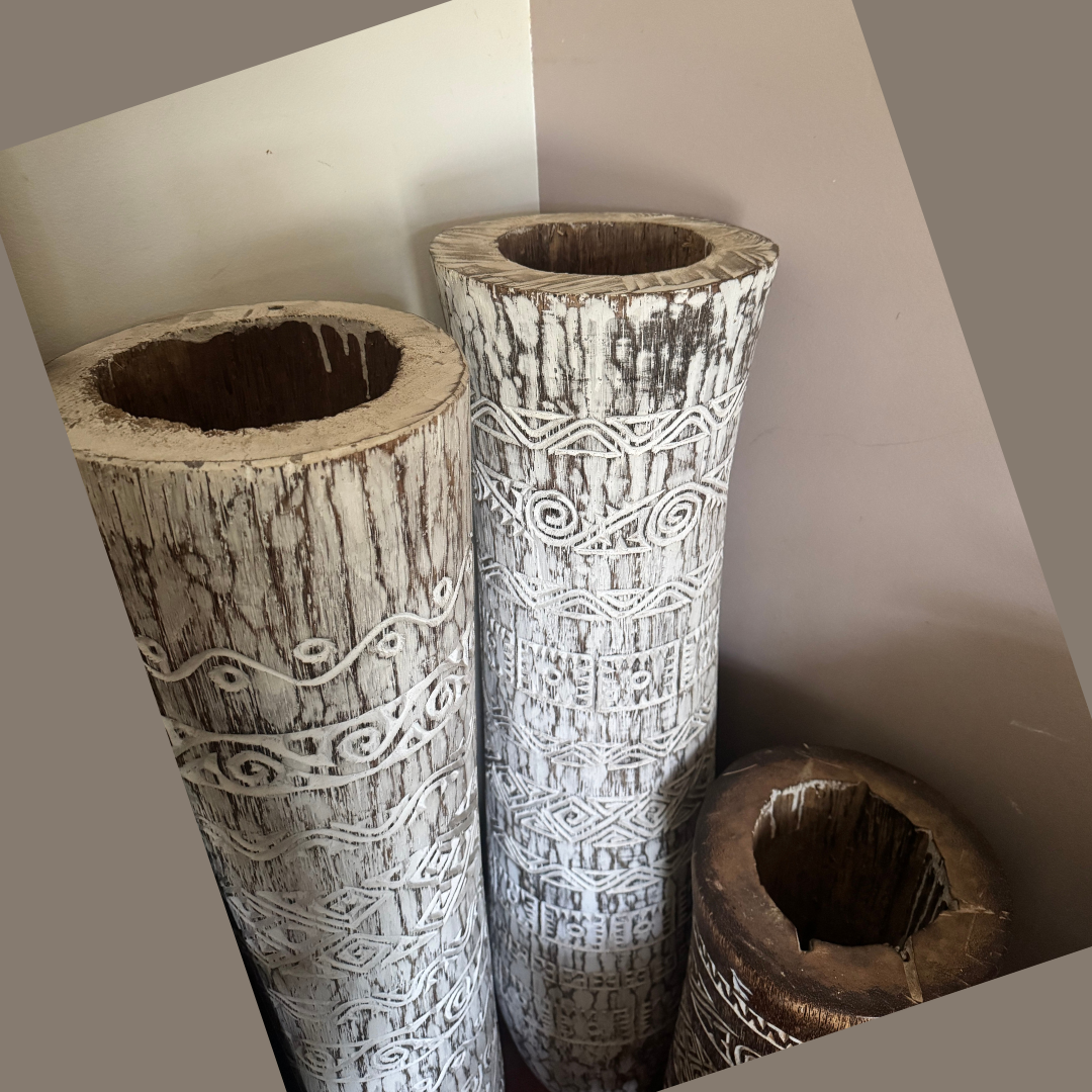 Overhead close-up of two whitewashed vessels and one dark brown vessel, showing hollow interiors, uneven rims and rustic grain
