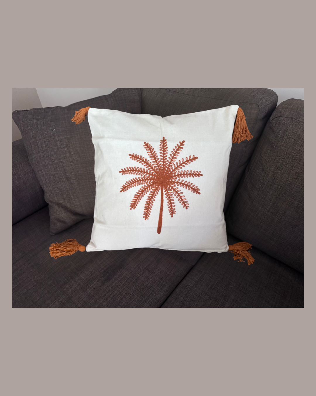 Decorative pillow with a brown leaf pattern on a gray couch