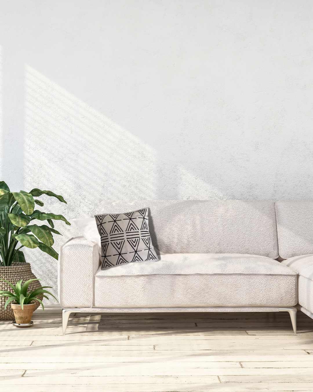 White sofa with a patterned pillow in a minimalistic room with plants and a white wall.