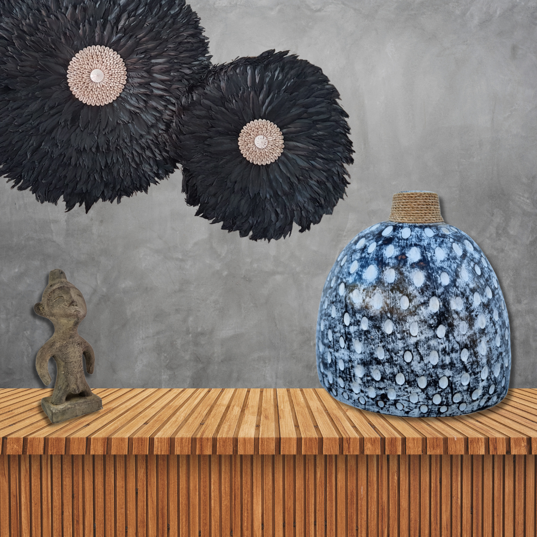 Decorative items including black feathered wall art and a blue textured vase on a wooden surface with a gray wall background.