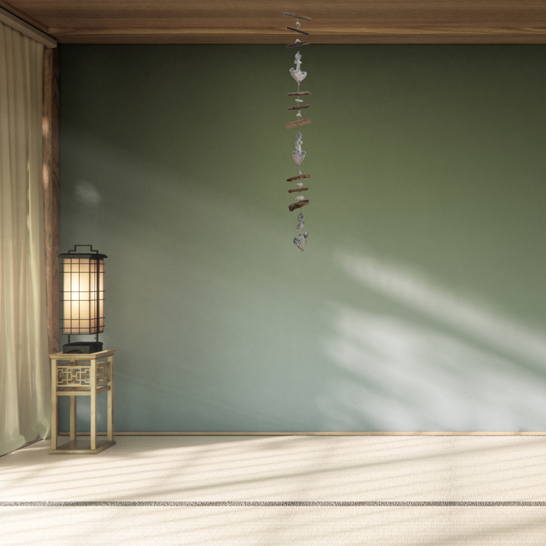 Decorative wind chime hanging in a room with a lamp and green wall.