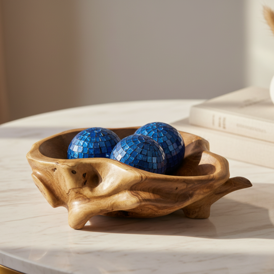 Three blue mosaic decorative balls resting inside a teak root tray on a styled tabletop display