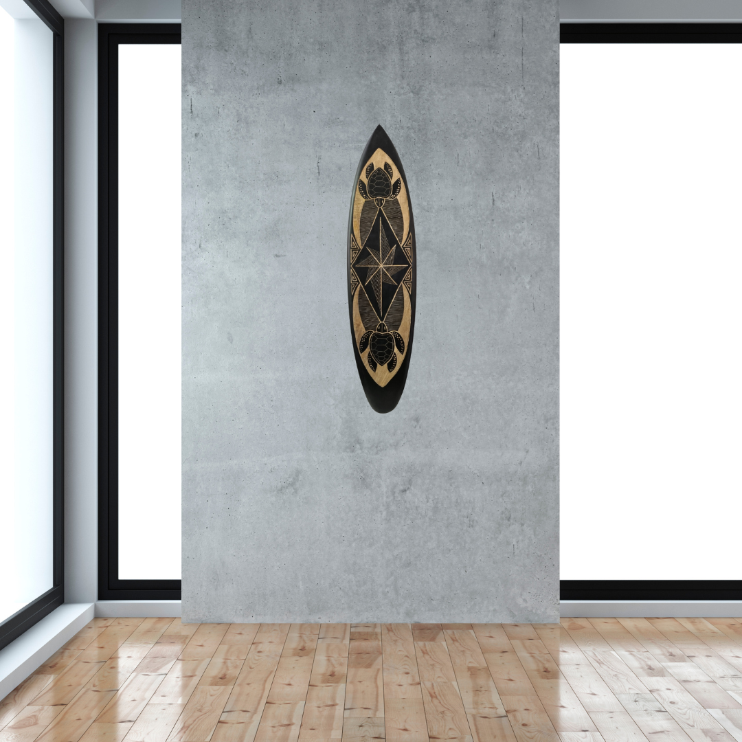 Hand-carved wooden surfboard wall art featuring turtles on either side of the midsection with adjoining mural-style decorative art, displayed on a soft grey wall