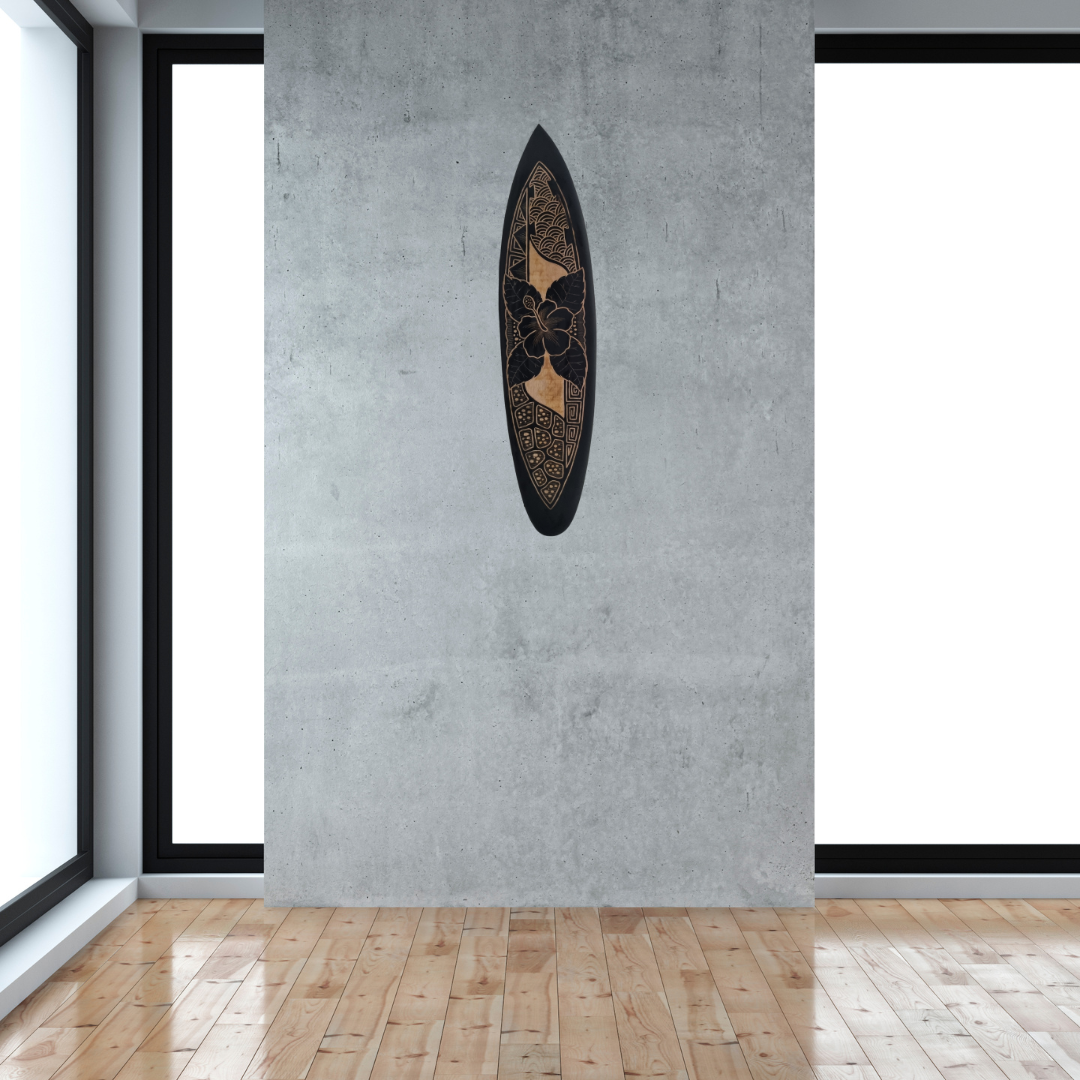 Hand-carved wooden surfboard wall art featuring a single hibiscus flower in the midsection with decorative floral scrolls, displayed hanging vertically on a soft grey wall
