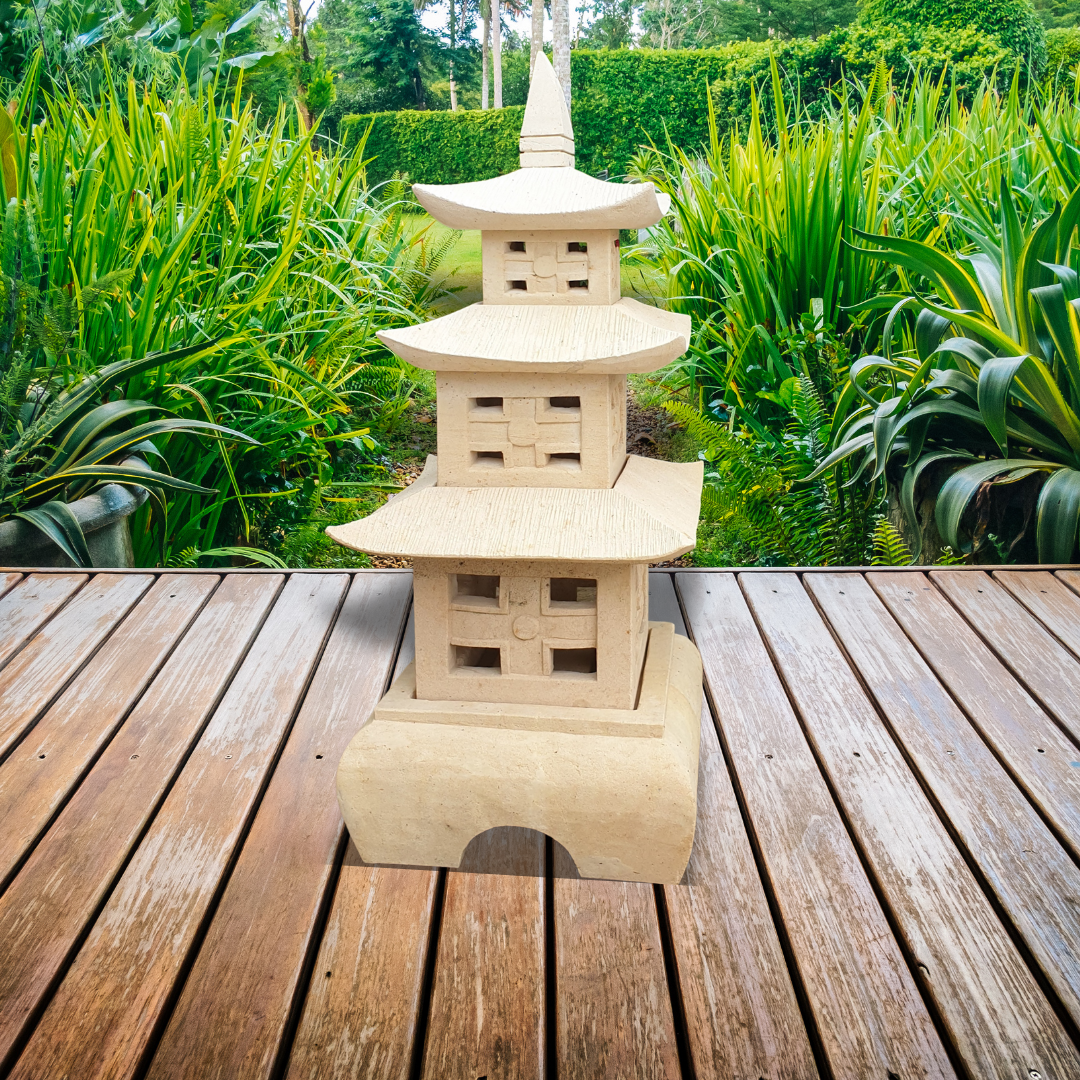 CarvingThree-tier stone pagoda sculpture on a weathered timber deck, surrounded by lush tropical garden greenery and ferns