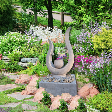Garden scene with a stone sculpture and colorful flowers