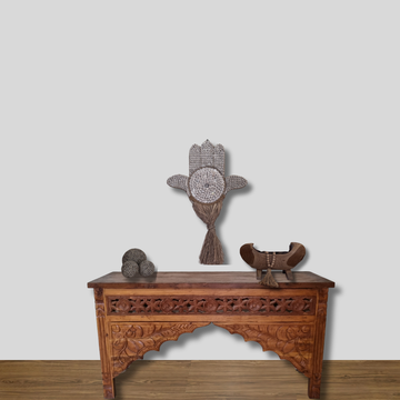 Carved wooden table with decorative items against a plain wall