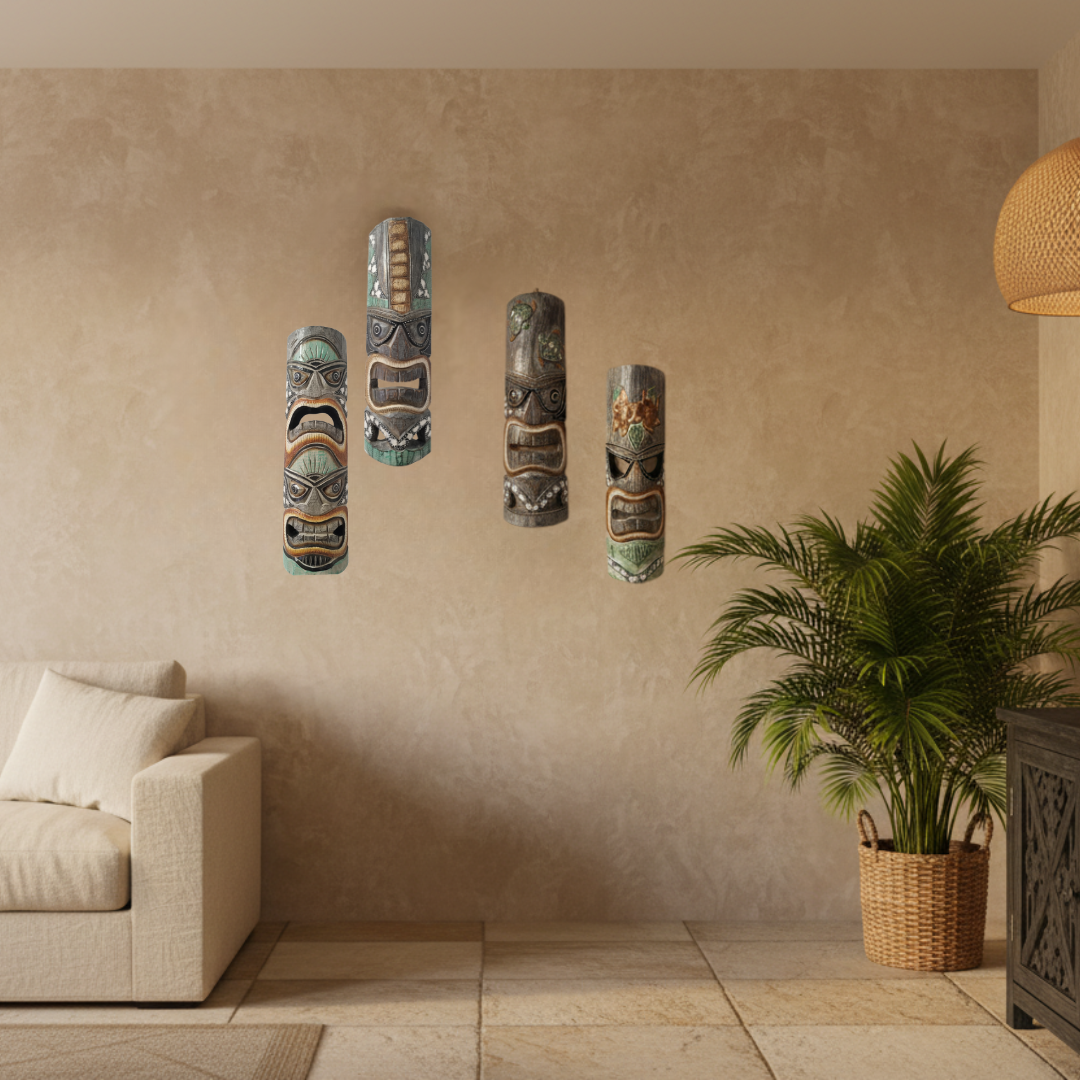 Four hand-carved wooden tiki masks arranged as a gallery wall display in a warm tropical living room, styled with a cream linen sofa, rattan pendant lamp, palm plant, and carved timber cabinet.
