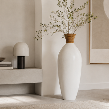White vase with green branches on a neutral background