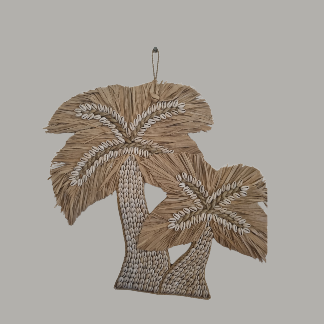 Close up of natural cowrie shell palm tree duo wall art styled against a warm beige background