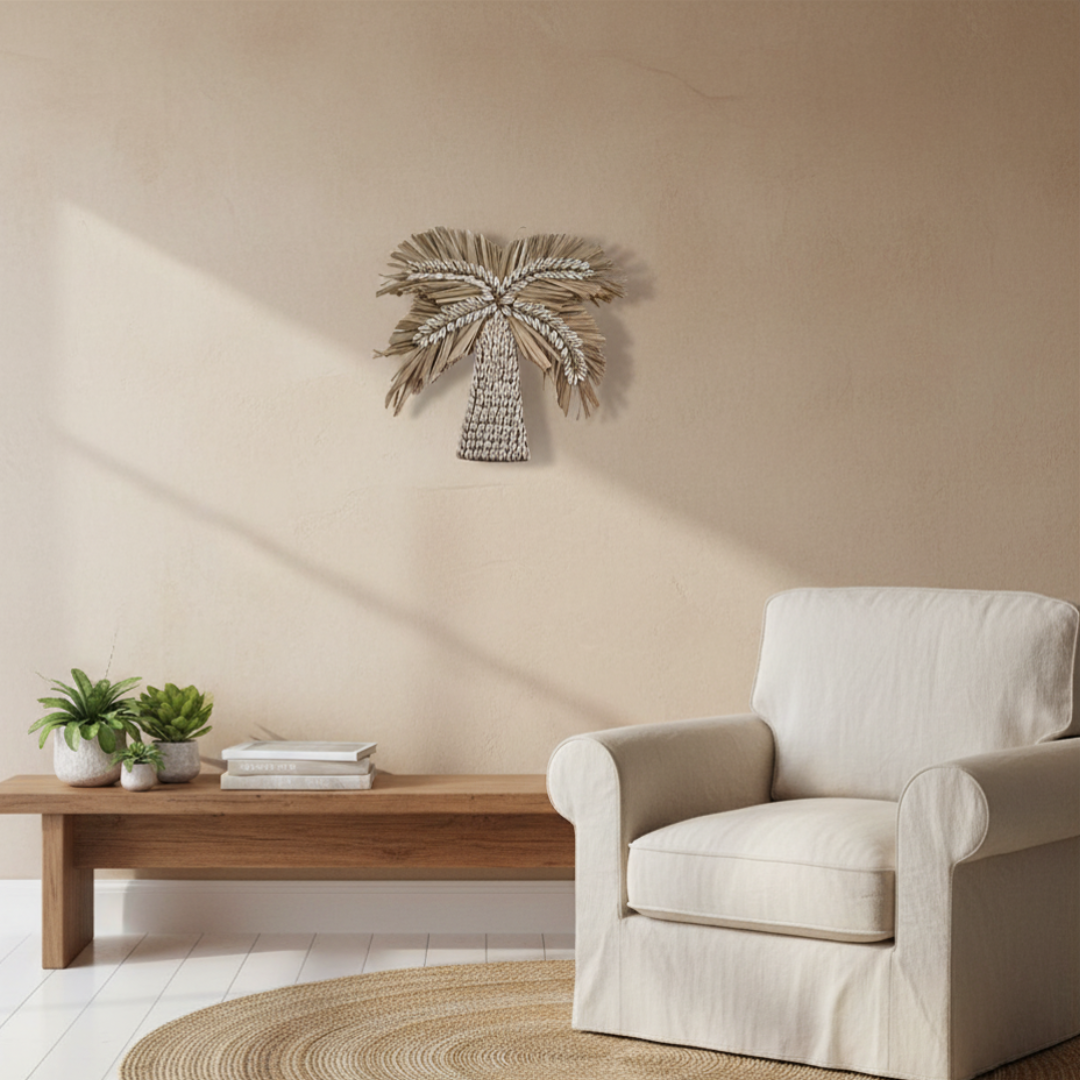 Natural cowrie shell palm tree wall art styled in a warm neutral living room above a timber bench with linen armchair