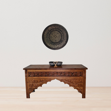 Decorative wooden table with intricate carvings on a plain background