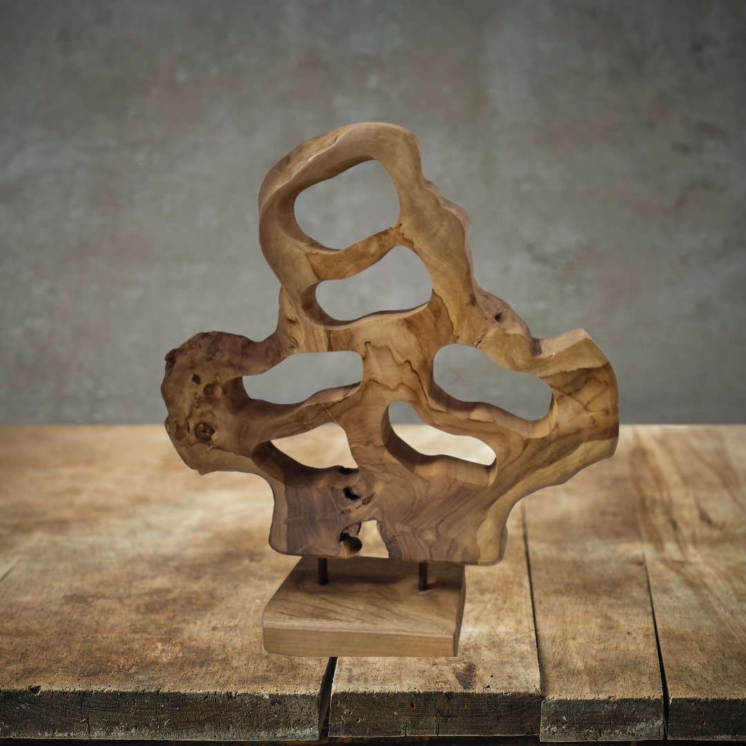 Teak Wood Table Top Sculpture displayed on a rustic timber surface against a grey concrete wall, showing natural teak grain and organic abstract form