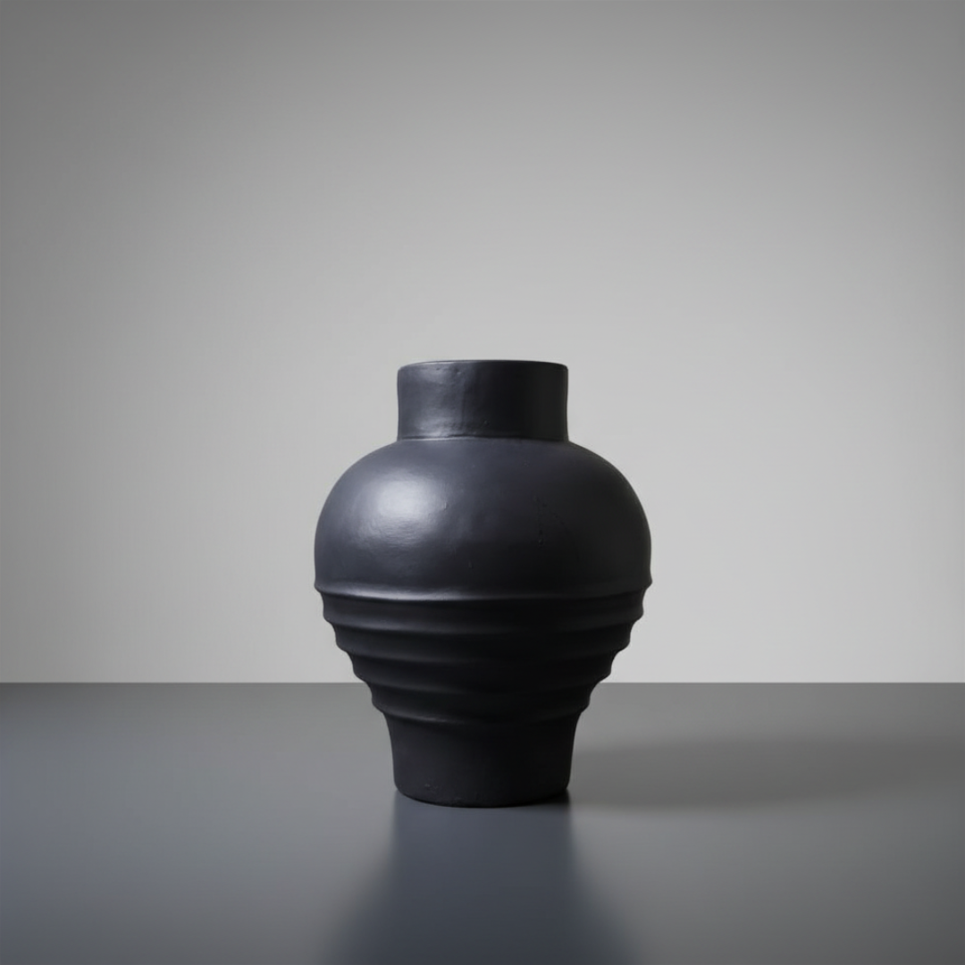 Black vase on a gray surface with a gray background