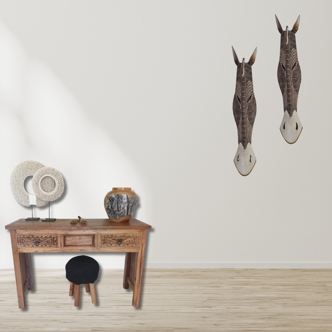  Two handcrafted wooden zebra style wall masks mounted above a wooden console table with decorative items – African style wall art Australia