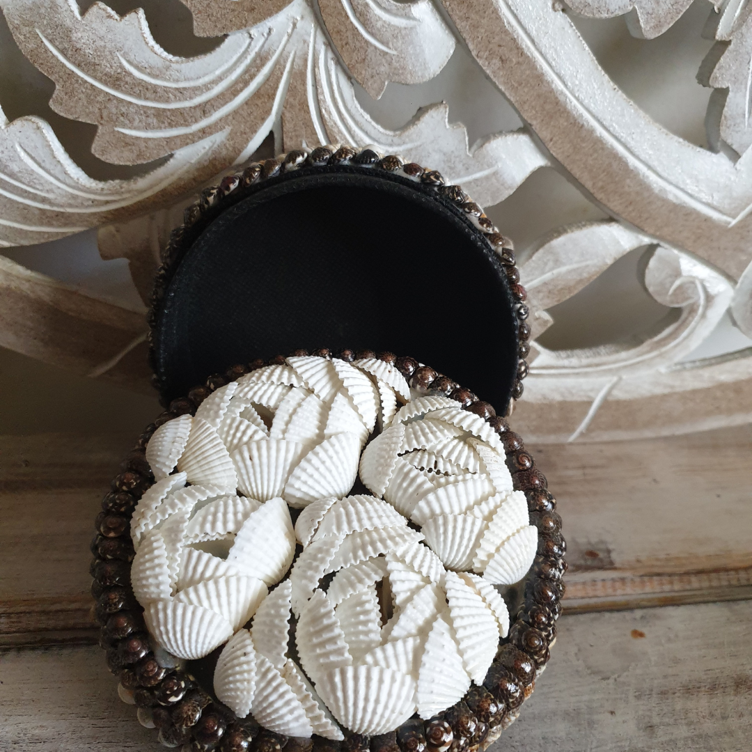 Open round trinket box with a black interior and a white shell-covered lid finished with dark beaded trim.