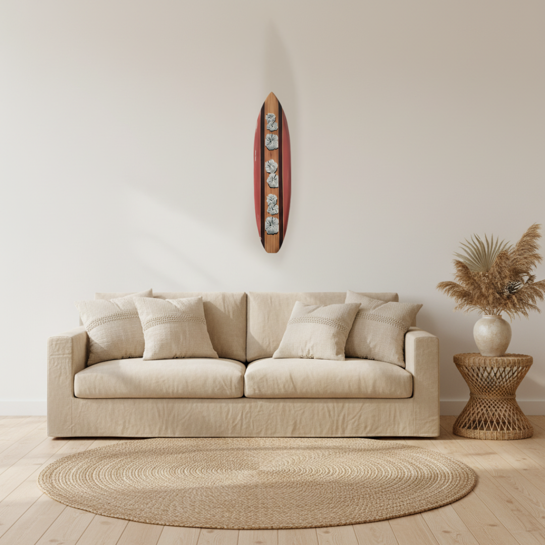 dusty pink surfboard wall art with carved white hibiscus flowers above a linen sofa