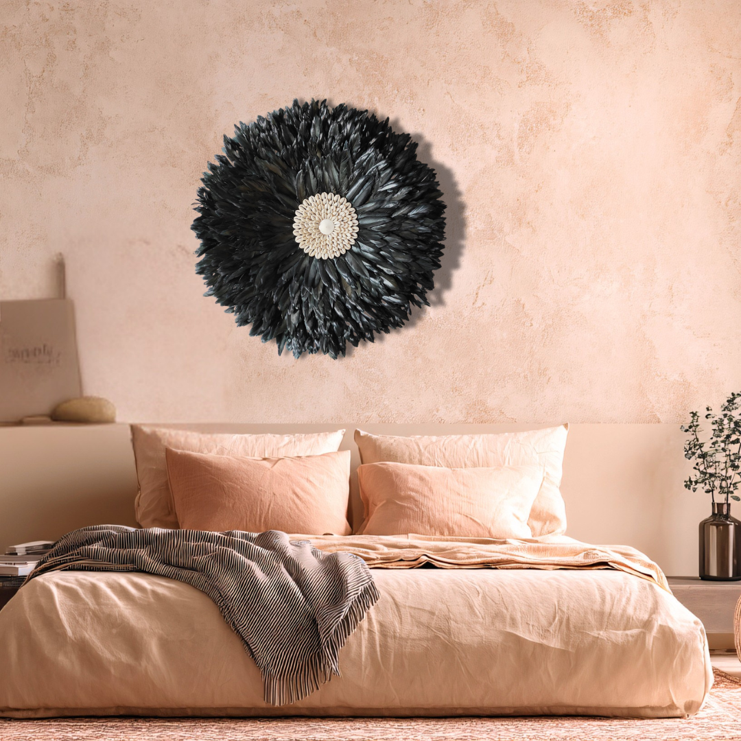 Large black handcrafted JUJU Hat with cowrie shell centre displayed as boho feather wall art above a bed in a warm earthy bedroom, Extra Large 60cm boho wall décor